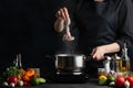 The chef in black apron puts fresh octopus in pot with boiling water on dark blue background. Backstage of cooking restaurant dish Royalty Free Stock Photo