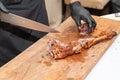 Chef in black gloves cuts juicy meat steak on the wood board with the knife, close-up. Delicious, juicy, freshly cooked meat Royalty Free Stock Photo