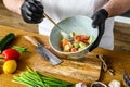 A chef in black gloves prepares a vegatarian vegetable salad. Concept of cooking healthy organic food Royalty Free Stock Photo