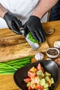 A chef in black gloves prepares a vegatarian vegetable salad. Concept of cooking healthy organic food Royalty Free Stock Photo