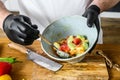 A chef in black gloves prepares a vegatarian vegetable salad. Concept of cooking healthy organic food Royalty Free Stock Photo