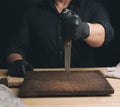 Chef in a black shirt and black latex gloves holds a large kitchen knife Royalty Free Stock Photo