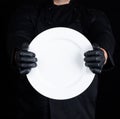 Chef in black uniform holding a round empty plate Royalty Free Stock Photo