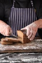 chef in black uniform holds a kitchen knife in his hand and cuts off pieces of bread Royalty Free Stock Photo