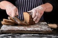 chef in black uniform holds a kitchen knife in his hand and cuts off pieces of bread Royalty Free Stock Photo