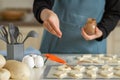 A chef in a blue apron sprinkles cinnamon on cookie dough blanks in a home private bakery