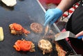Chef with blue gloves cooking burger with tomatoes
