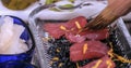 Chef brushes soy sauce over raw tuna on a bed of sea weeds