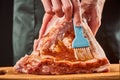 Chef brushing beef ribs with sauce to marinate them