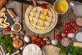 The chef brushing pie with chicken and mushrooms on wooden table with variety of ingredients background. Concept of cooking