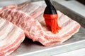 Chef brushing raw beef ribs with marinade