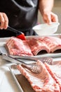 Chef brushing raw beef ribs with marinade