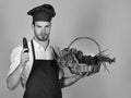 Chef in burgundy uniform holds cucumber. Natural food concept.