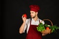 Chef in burgundy uniform holds red pepper in hand.