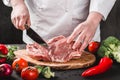 Chef Butcher cutting pork meat with knife on kitchen, cooking food. Royalty Free Stock Photo