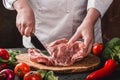 Chef Butcher cutting pork meat with knife on kitchen, cooking food Royalty Free Stock Photo