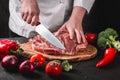 Chef Butcher cutting pork meat with knife on kitchen, cooking food Royalty Free Stock Photo