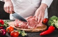 Chef Butcher cutting pork meat with knife on kitchen, cooking food Royalty Free Stock Photo