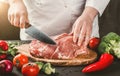 Chef Butcher cutting pork meat with knife on kitchen, cooking food. Toning. Royalty Free Stock Photo