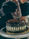 chef cake decorator squeezing a bottle containing chocolate ganache on a cake Royalty Free Stock Photo