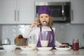 Chef child lick spoon cooking healthy meal and dinner preparation. Child chef cook is learning how to make a cake in the Royalty Free Stock Photo