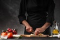 Chef chopping garlic for cooking. Against the background of a gray wall, and vegetables. Cooking and recipe book