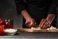 Chef chopping garlic for cooking. Against the background of a gray wall, and vegetables. Cooking and recipe book Royalty Free Stock Photo