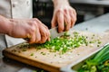 chef chopping green onions on a chopping board for a dish