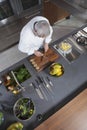 Chef Chopping Kiwi On Board At Commercial Kitchen Counter