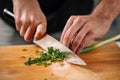 Chef chopping spring onion on wooden board