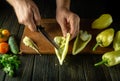 The chef cleans yellow fresh peppers on a cutting board with a knife to prepare a delicious vegetable dish. The concept of cooking