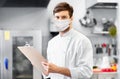 Chef with clipboard in face mask at restaurant