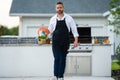 Chef in cook apron preparing salmon fish on barbecue grill outdoor. Man cooking tasty food on barbecue grill at backyard Royalty Free Stock Photo