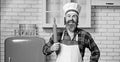 Chef cook with beard holds a rolling-pin on white kitchen.