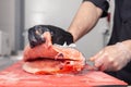 Closeup whole fresh salmon fish preparing fillet with knife on red cutting board in professional kitchen of restaurant. Concept Royalty Free Stock Photo