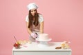 Chef cook confectioner or baker in white t-shirt toque chefs hat cooking at table isolated on pink pastel background in