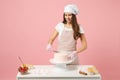 Chef cook confectioner or baker in white t-shirt toque chefs hat cooking at table isolated on pink pastel background in