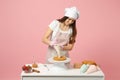 Chef cook confectioner or baker in white t-shirt toque chefs hat cooking at table isolated on pink pastel background in