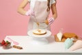 Chef cook confectioner or baker in white t-shirt toque chefs hat cooking at table isolated on pink pastel background in