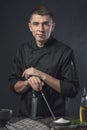 Chef cook holds a knife over dark grey background
