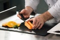 Chef cook orange cake at kitchen restaurant. Closeup chef hands decorating cake. Royalty Free Stock Photo