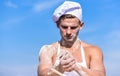 Chef cook preparing dough for baking with flour. Man on busy face wears cooking hat and apron, sky on background. Baker Royalty Free Stock Photo