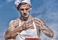 Chef cook preparing dough for baking with flour. Man on busy face wears cooking hat and apron, sky on background. Cook Royalty Free Stock Photo