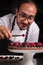 Chef cook preparing tart in his kitchen. Delicious raspberry tart tartlet with whipped cream.