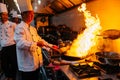 Chef cooking Chinese food with burning fire on steel pan