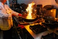 Chef cooking Chinese food with burning fire on steel pan