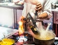 Chef cooking with flame in a frying pan on a kitchen stove Royalty Free Stock Photo