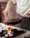 Chef cooking with flame in a frying pan on a kitchen stove Royalty Free Stock Photo