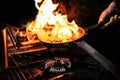 Chef cooking with flame in a frying pan on a kitchen stove Royalty Free Stock Photo