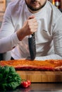 Chef cooking raw meat in the kitchen. chef holds a professional kitchen knife. Concept of Cooking process and preparing dishes Royalty Free Stock Photo